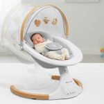 Jool Baby Nova Nature electric baby swing with newborn calmly swaying side to side under canopy