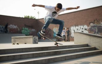 Young skater performing an ollie over stairs on a popsicle skateboard during street session