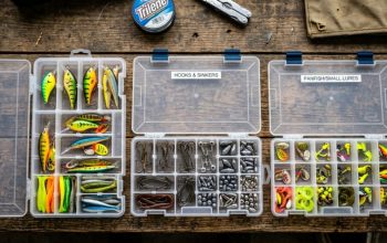 Open tackle backpack with stacked organized utility trays on boat deck.