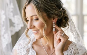 Bride touching sparkling diamond-drop earrings on her wedding day.