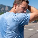 Commuter walking along sunny Denver street wearing breathable performance dress shirt.
