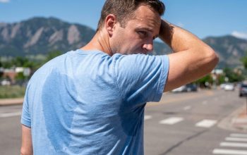 Commuter walking along sunny Denver street wearing breathable performance dress shirt.