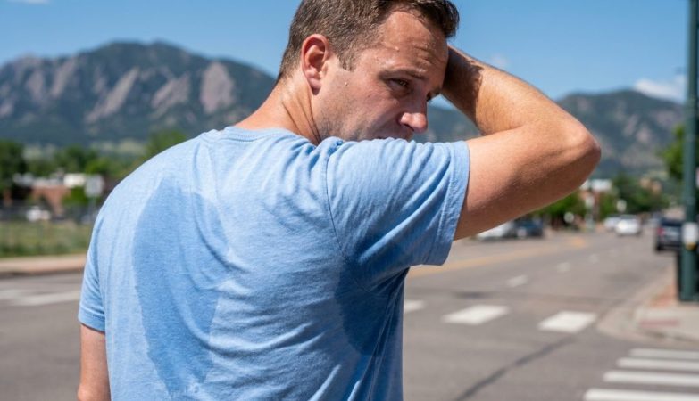 Commuter walking along sunny Denver street wearing breathable performance dress shirt.